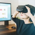 woman using black VR headset beside computer